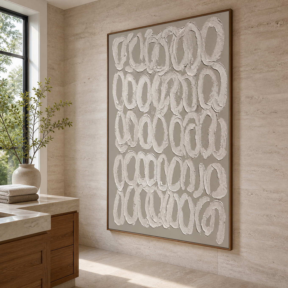 Wood framed white loop artwork beside a stone vanity in a sunlit bathroom dry area.
