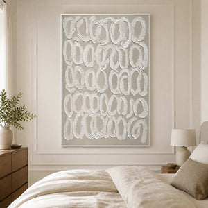 White framed textured loop artwork on a paneled bedroom wall beside a neutral bed.