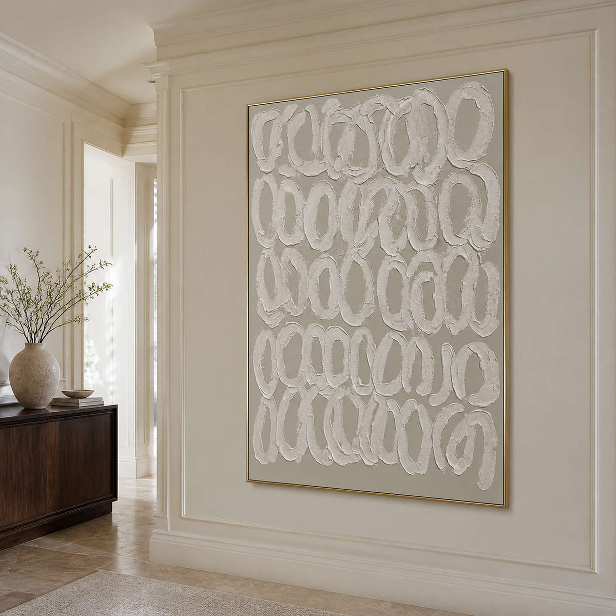 Gold framed minimalist loop artwork on a cream paneled wall in a bright hallway.