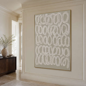 Gold framed minimalist loop artwork on a cream paneled wall in a bright hallway.