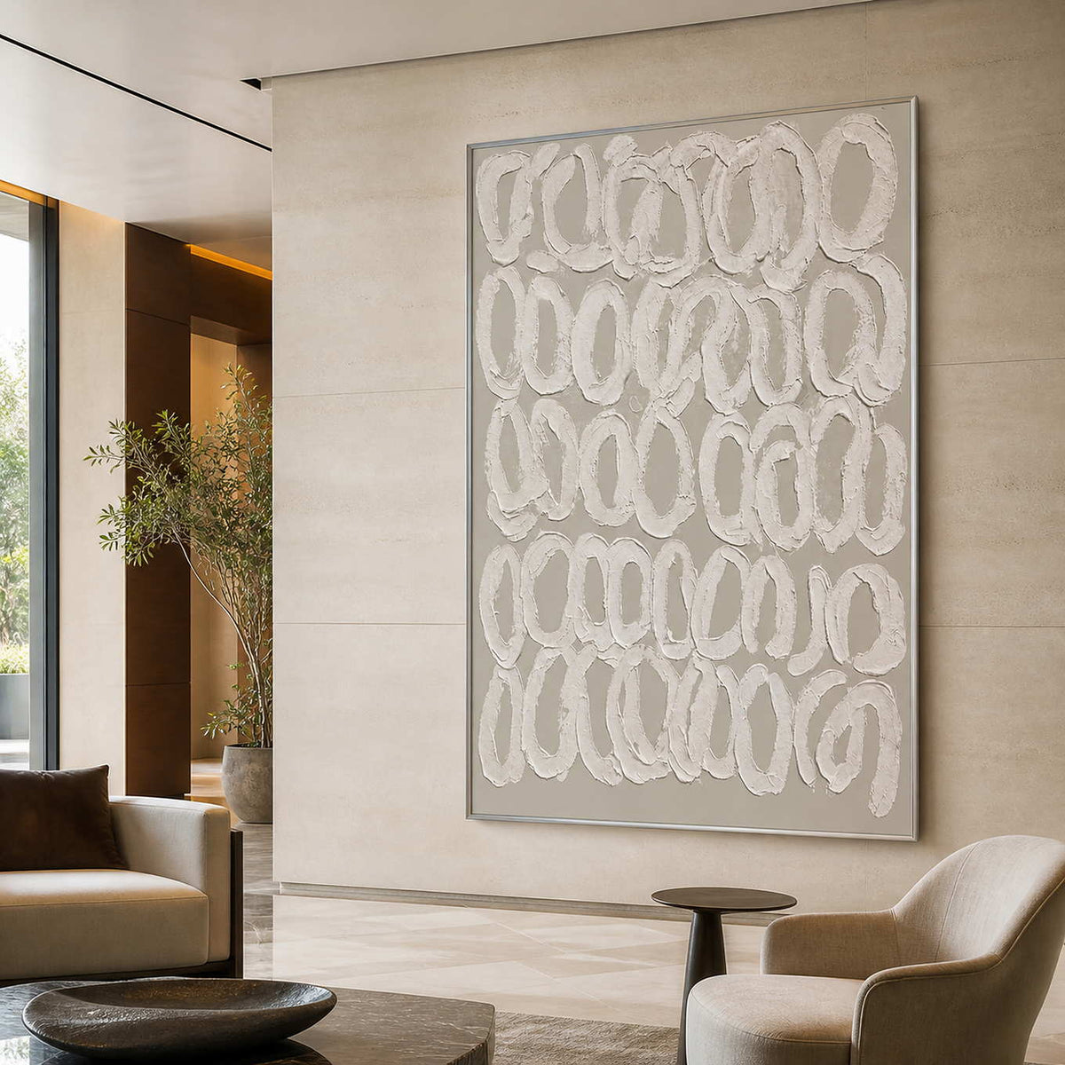 Silver framed textured loop artwork above neutral seating in a spacious hotel lounge.