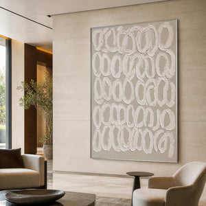 Silver framed textured loop artwork above neutral seating in a spacious hotel lounge.