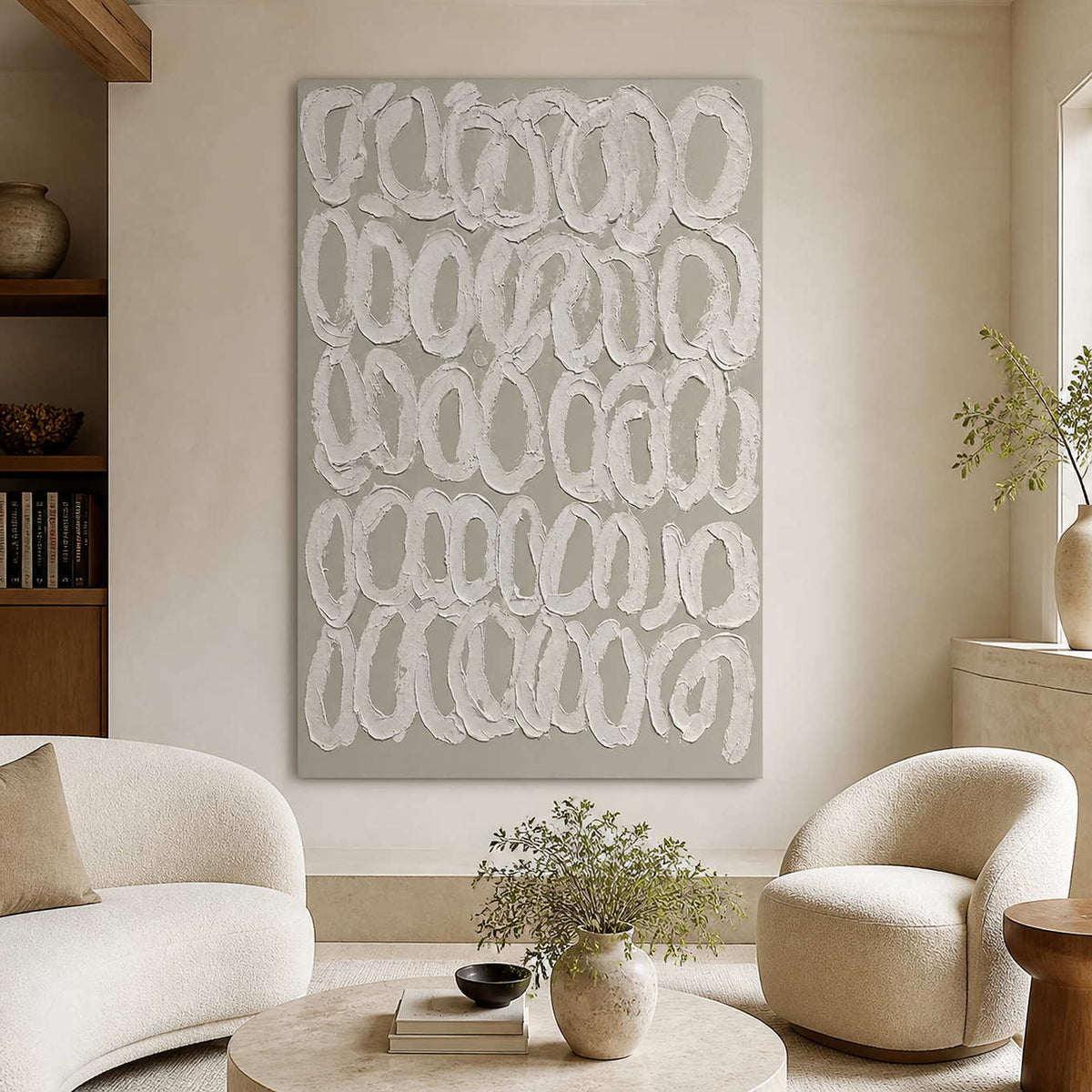 Frameless white loop artwork between cream living room chairs beside a bright window.