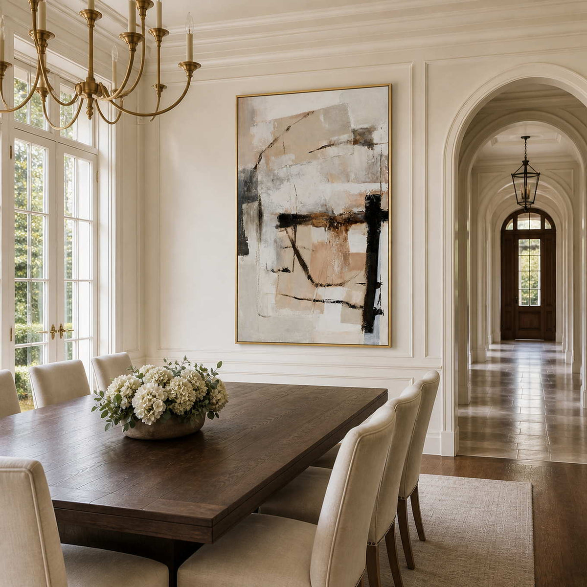 Gold framed cream and beige abstract artwork above a wooden dining table with white flowers.