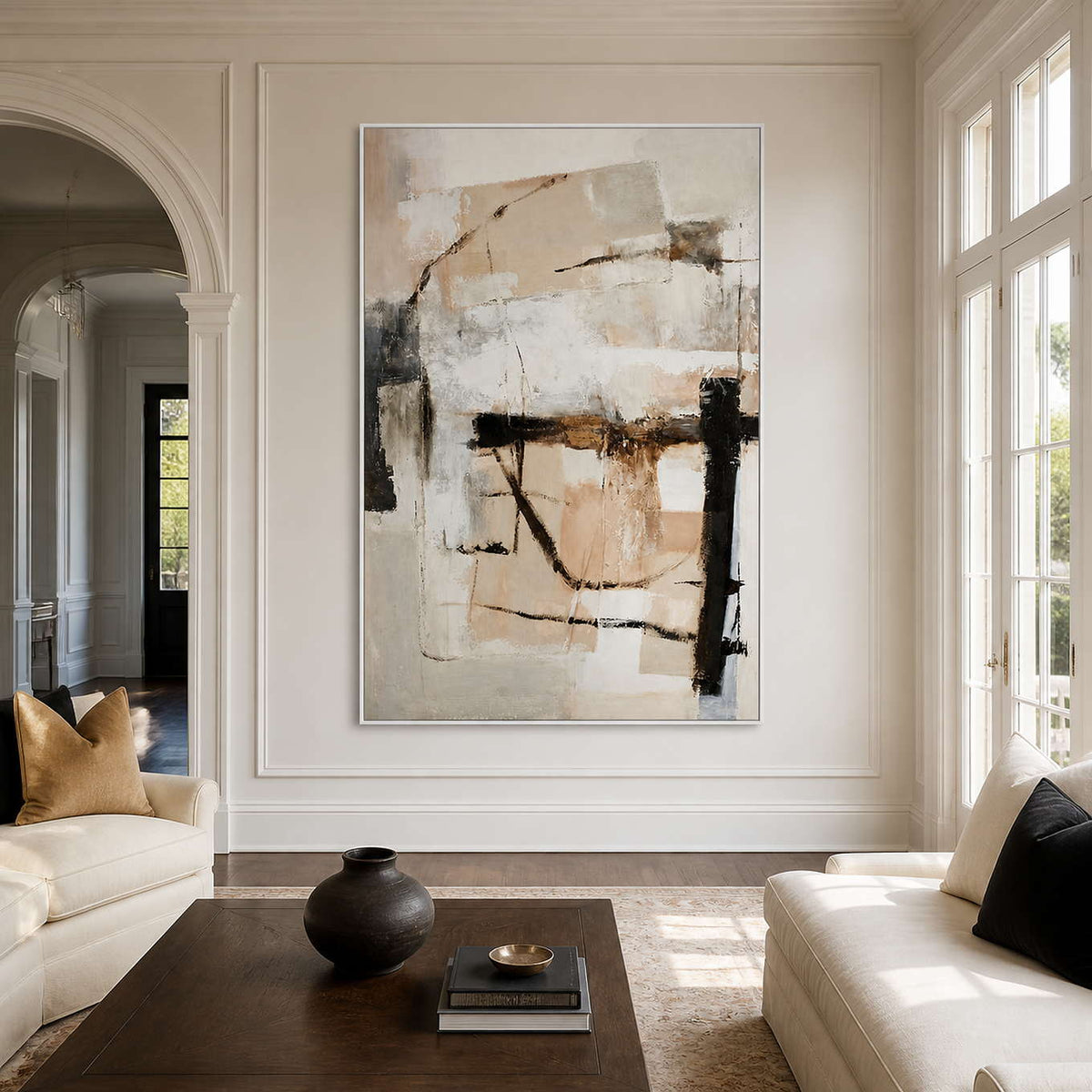 White framed cream and gray abstract artwork between pale sofas in an airy sitting room.