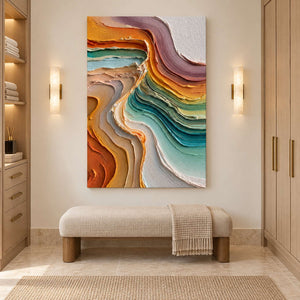 Vertical colorful artwork above a cream bench between paired wall sconces and wood cabinetry.