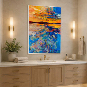 White framed vivid sunset painting above a bathroom vanity between warm wall lights.