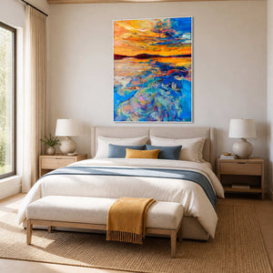 White framed blue and orange coastal artwork above cream bedding with matching accents.
