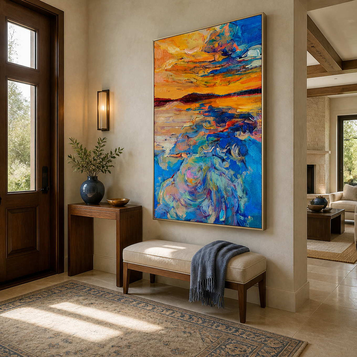Silver framed vertical sunset artwork above an entry bench with a blue throw.