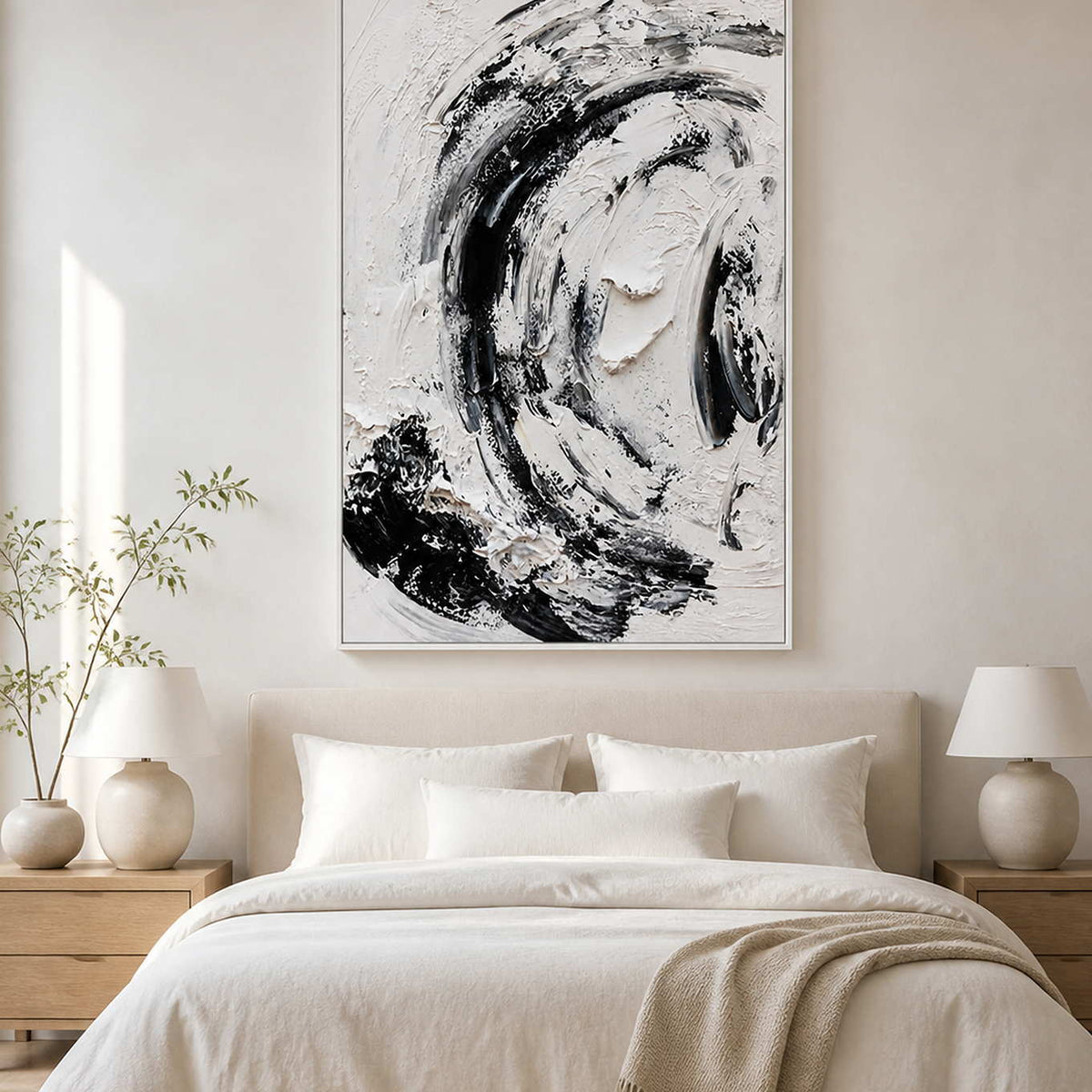 White framed monochrome painting above a cream bed with matching lamps and pale bedding.