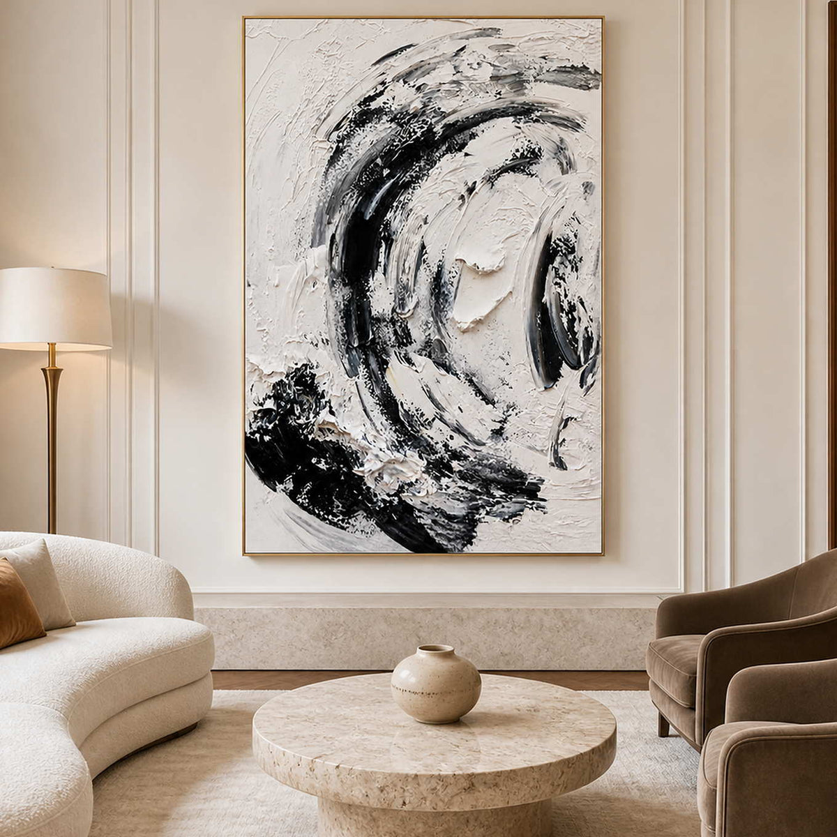 Gold framed black and white abstract painting beside a curved sofa and round stone table.