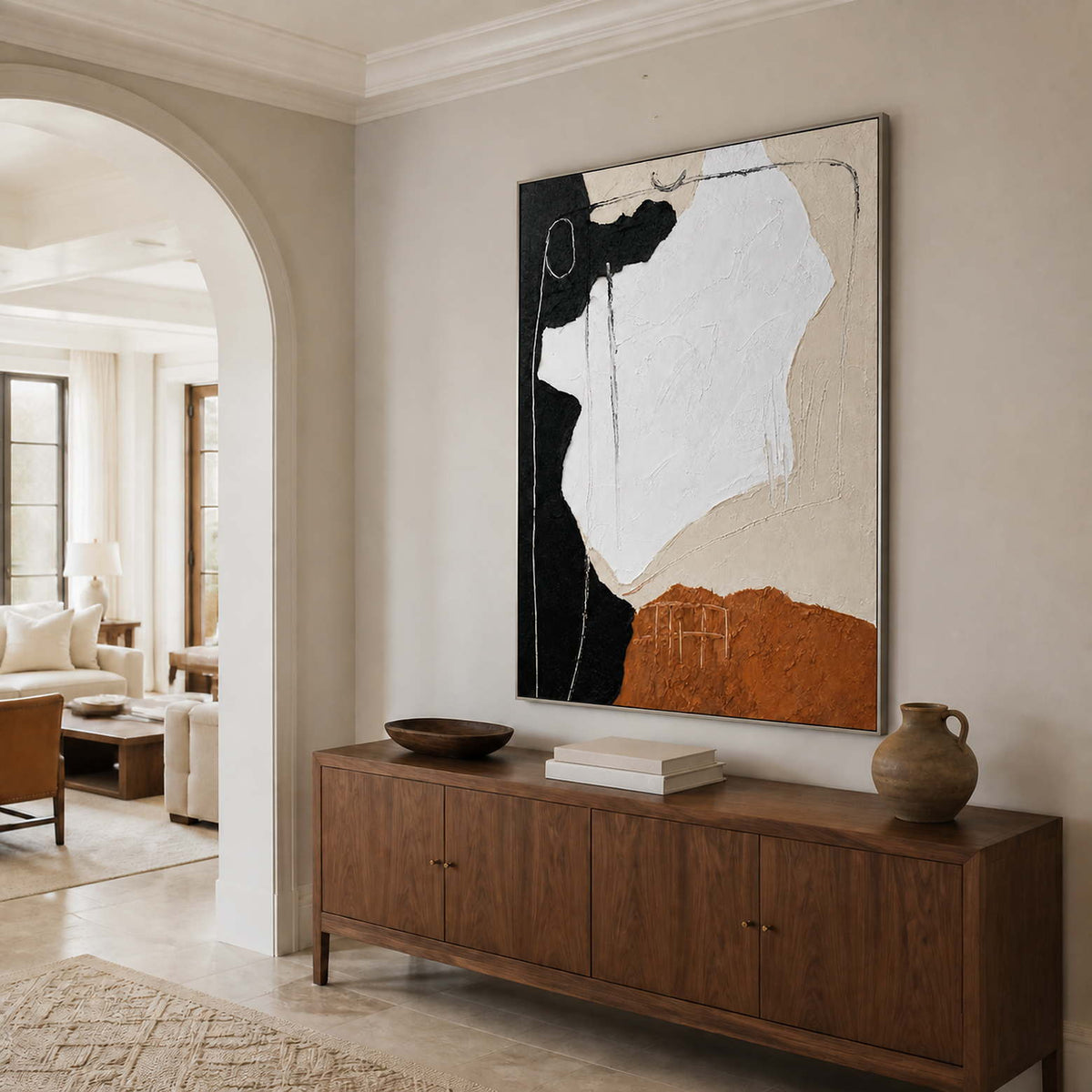 Silver-framed abstract wall art above a wooden console beside an arched doorway.