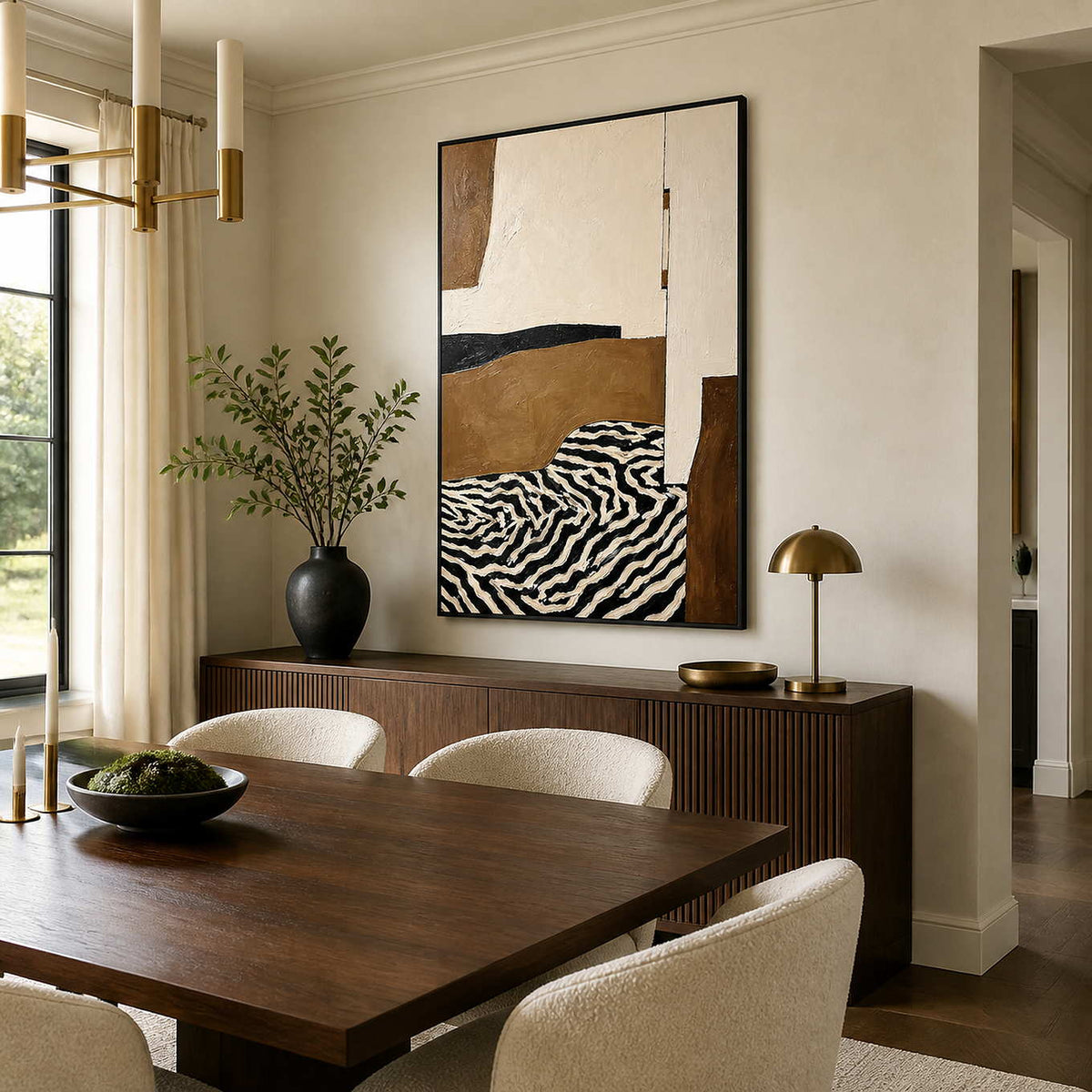 Black-framed cream and brown abstract painting above a fluted wooden dining room sideboard.