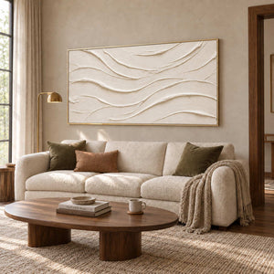 An Unhurried Flow in a gold frame above a cream sofa with olive cushions and a low oval wood coffee table.
