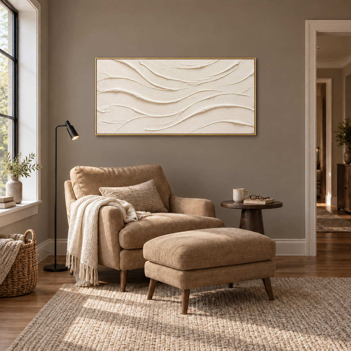 An Unhurried Flow in a gold frame above a tan armchair and matching footstool beside a small round table.
