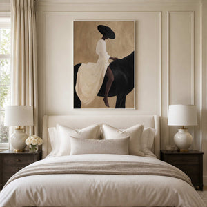 White framed rider and horse painting above a cream upholstered bed.