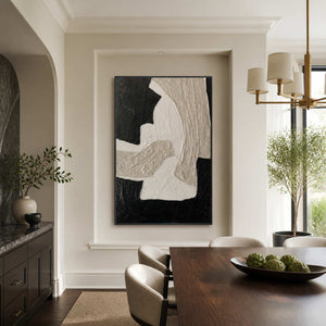 Black framed textured abstract painting beside a wooden dining table with artichokes.