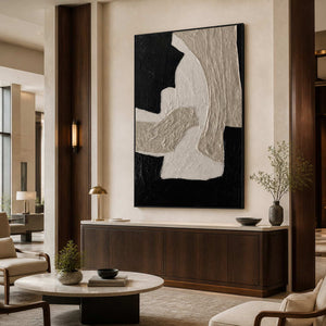 Black framed vertical abstract artwork above a cabinet in a hotel lounge.