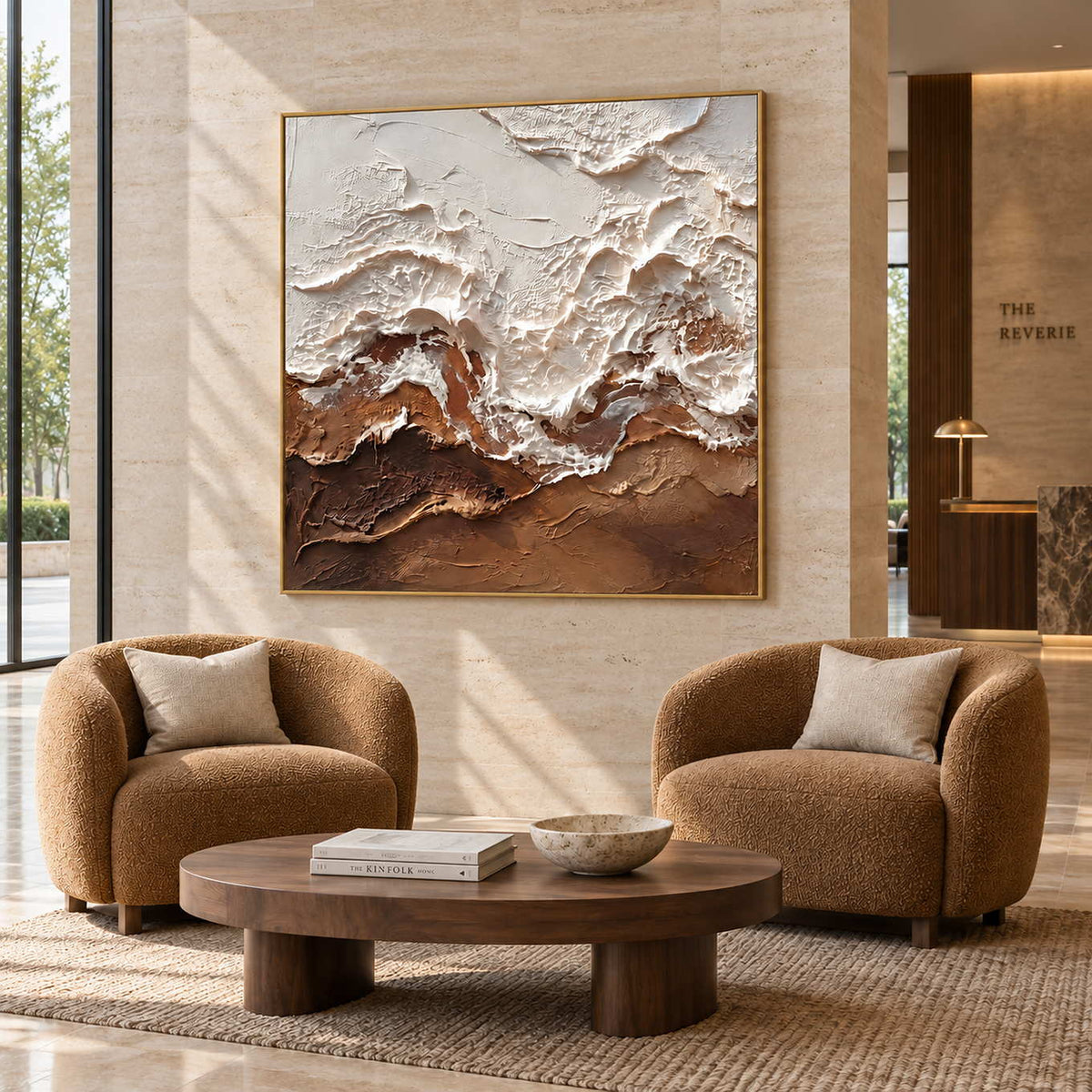 At Ease in a gold frame above two tan armchairs and a round wood coffee table in a commercial lobby.