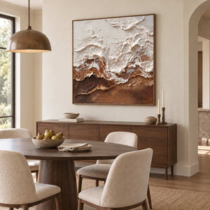 At Ease in a wood frame above a sideboard behind a round wood dining table and cream chairs.