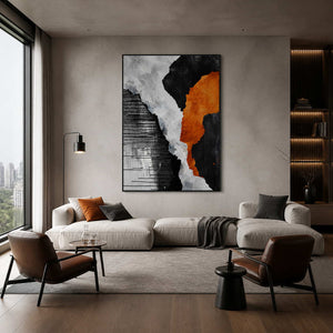 Black framed orange and monochrome abstract artwork above a pale sofa beside city-facing windows.