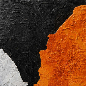Close view of textured orange paint meeting black and white areas along uneven edges.