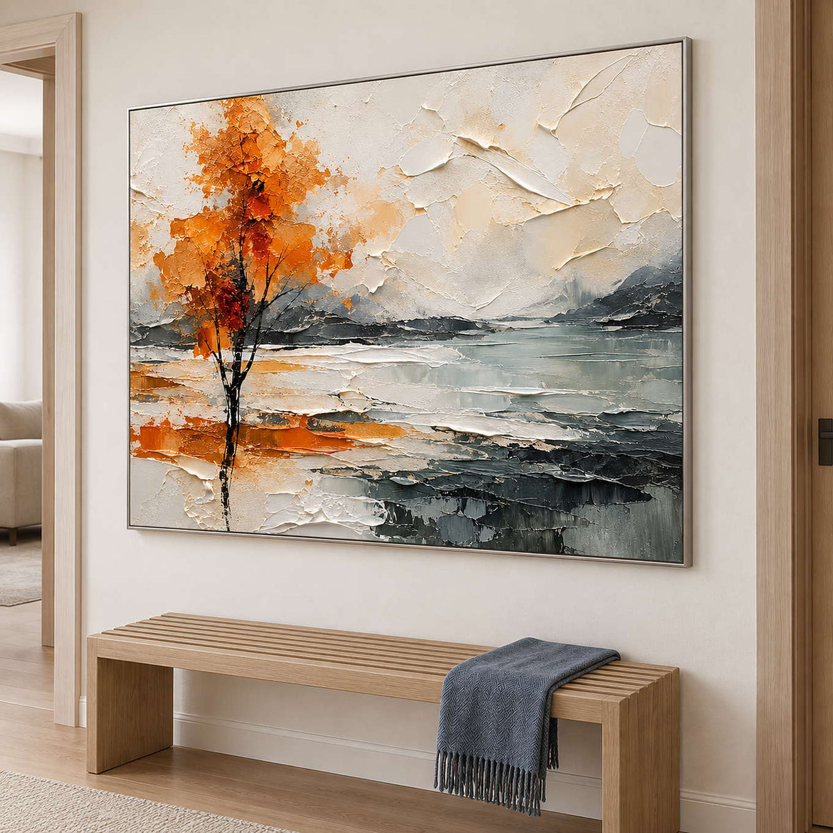 An orange autumn tree reflected beside a gray lake in a silver frame, displayed in a hallway.