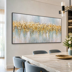 Black framed gold and pale blue artwork beside a stone table and blue dining chairs.