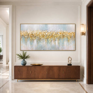 Gold framed panoramic abstract painting above a wood cabinet with blue and white ceramics.
