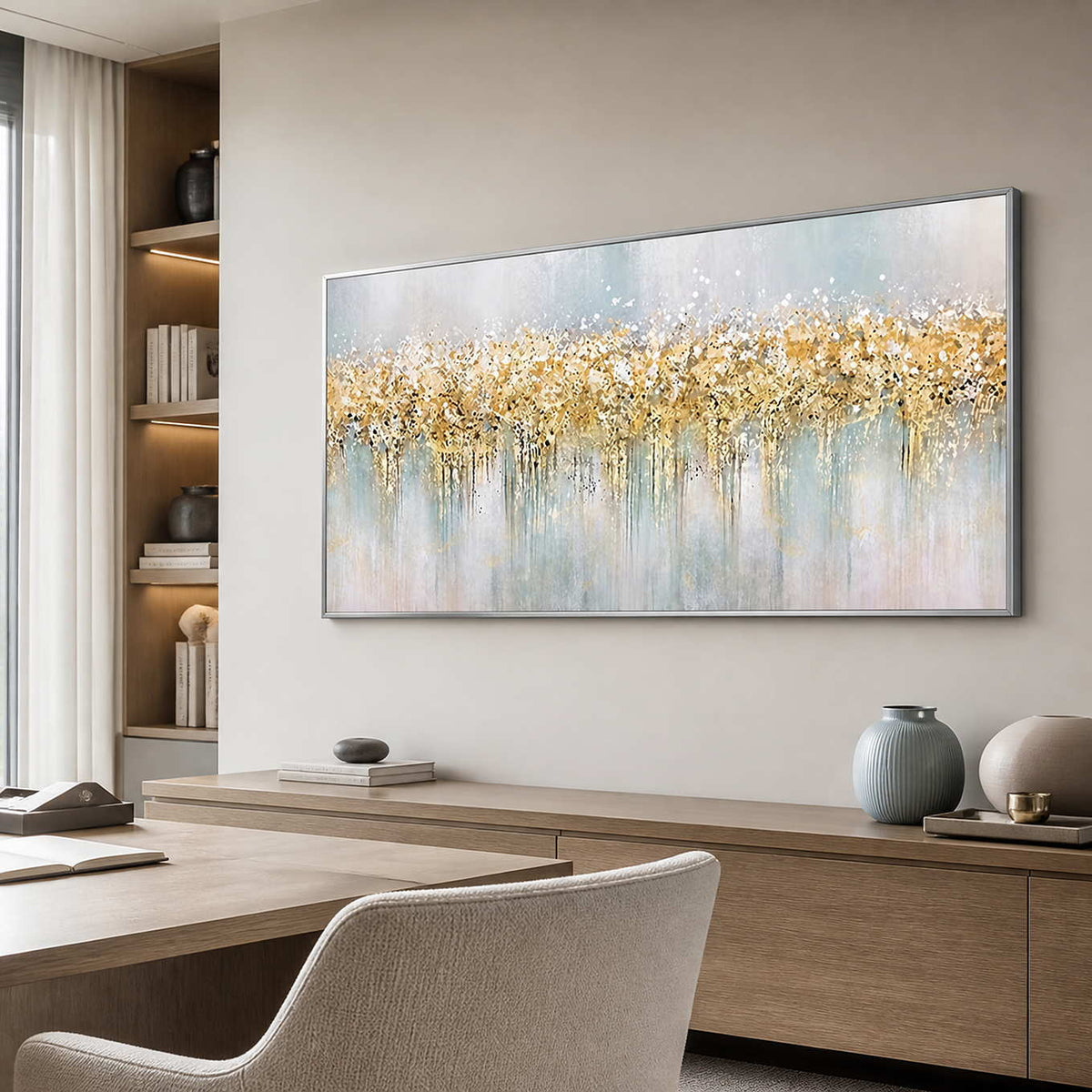 Silver framed pale blue and gold painting above a wood sideboard beside a study desk.