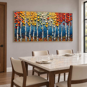 Autumn tree artwork beside a pale dining table and cream chairs.