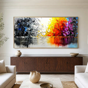 Gold-framed autumn lake painting above a dark cabinet between pale living room sofas.