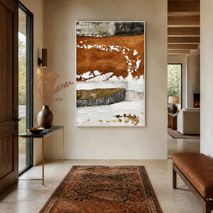 White framed rust abstract artwork beside a narrow console and leather bench in an entryway.