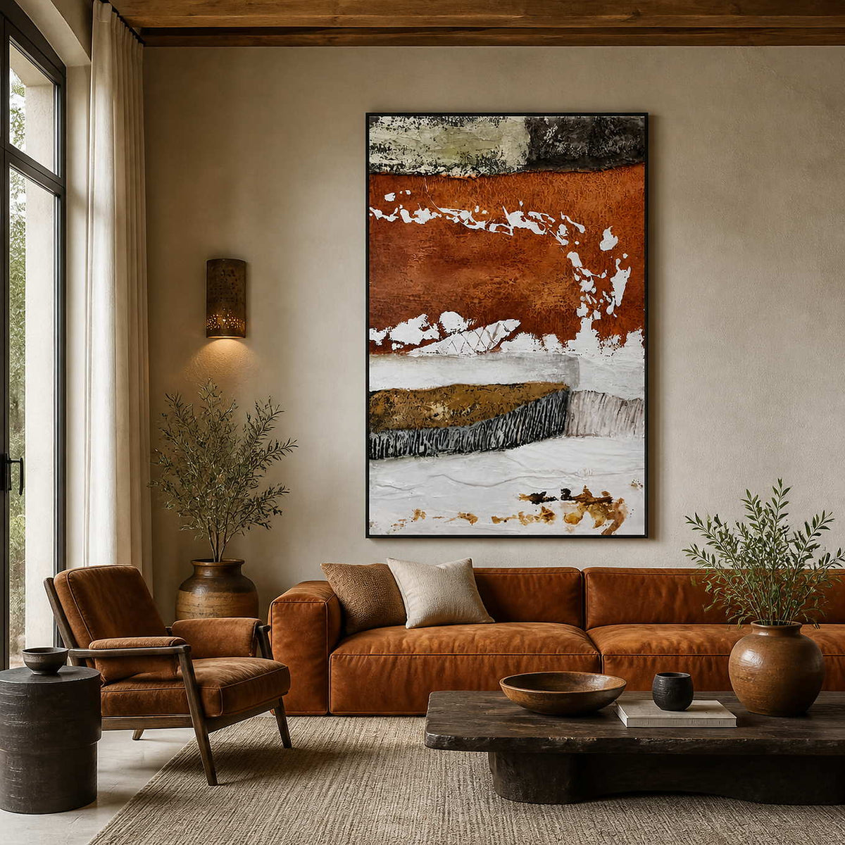Black framed rust and white abstract artwork above a warm leather sofa beside tall windows.