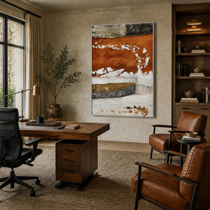 Silver framed textured abstract artwork beside a wooden office desk and leather reading chairs.