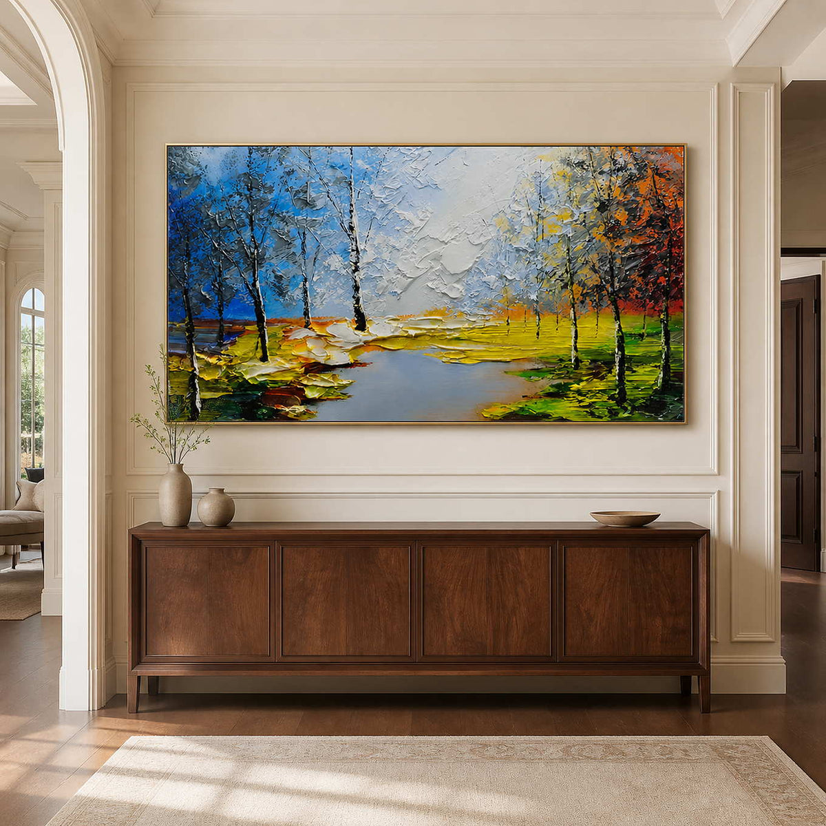 Gold framed landscape painting with blue water and orange trees above a hallway console.