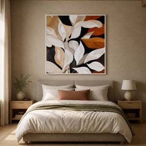 White framed cream and rust botanical painting above a softly upholstered bedroom headboard.