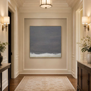 Gold framed charcoal gray abstract painting at the end of a softly lit hallway.