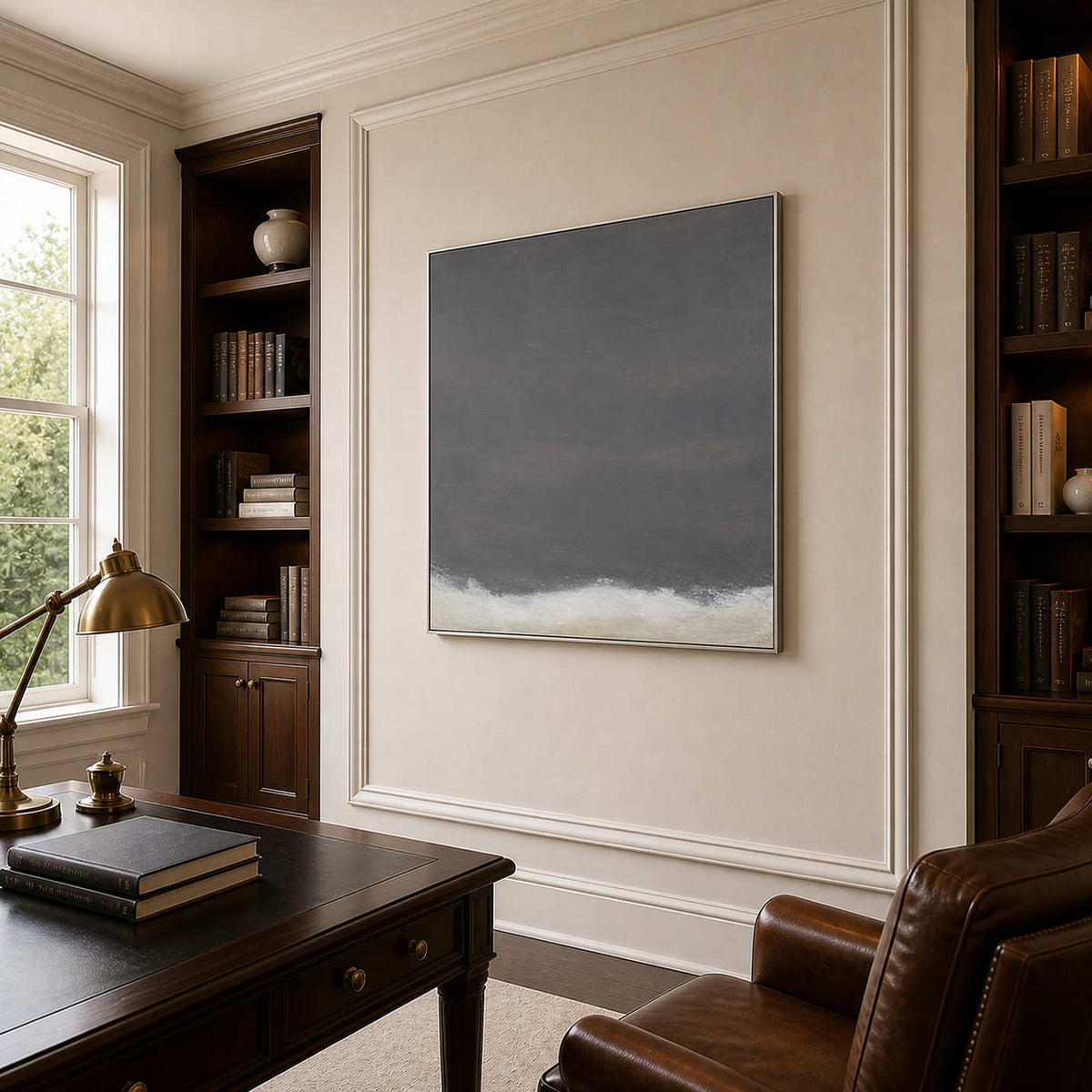 Silver framed minimalist gray painting between walnut bookshelves in a quiet home office.