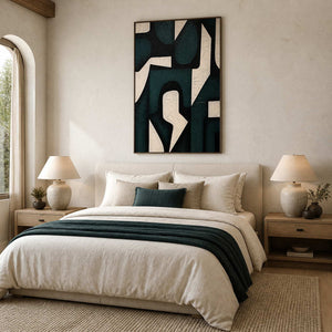 Wood framed dark green abstraction above a linen bed with a green throw.