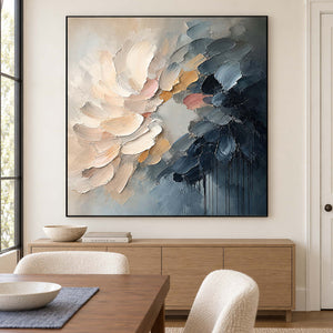 Layered cream and blush petals fading into deep blue in a black frame, displayed above a dining table.