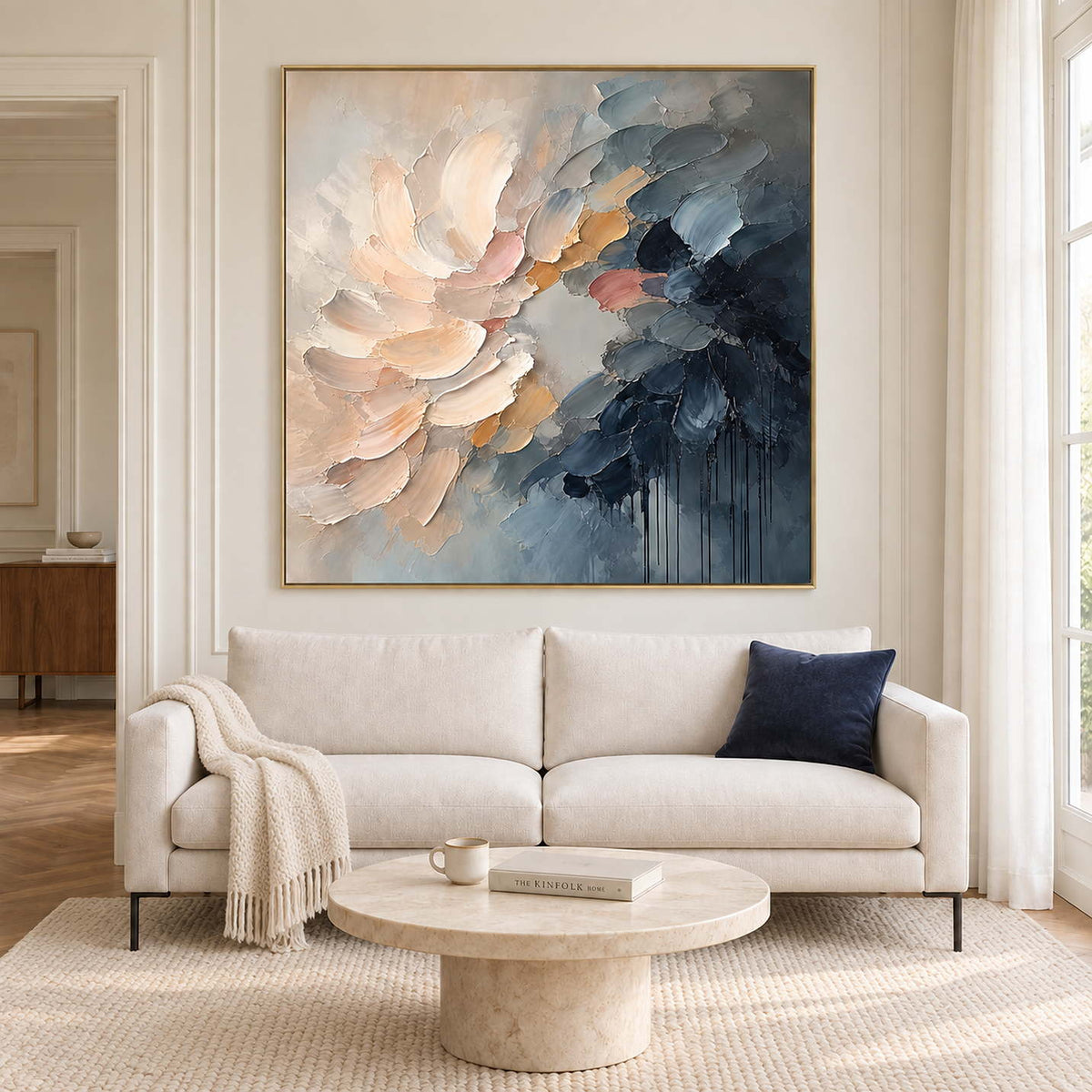 Layered cream and blush petals fading into deep blue in a gold frame, displayed above a sofa in a living room.