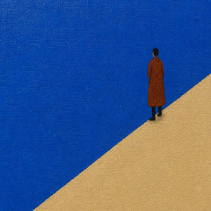Close-up of the rust-red figure against cobalt blue and warm sand.