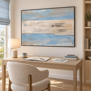 Pale blue and ivory coastal abstract painting with sand and charcoal bands in a black frame in a home office.