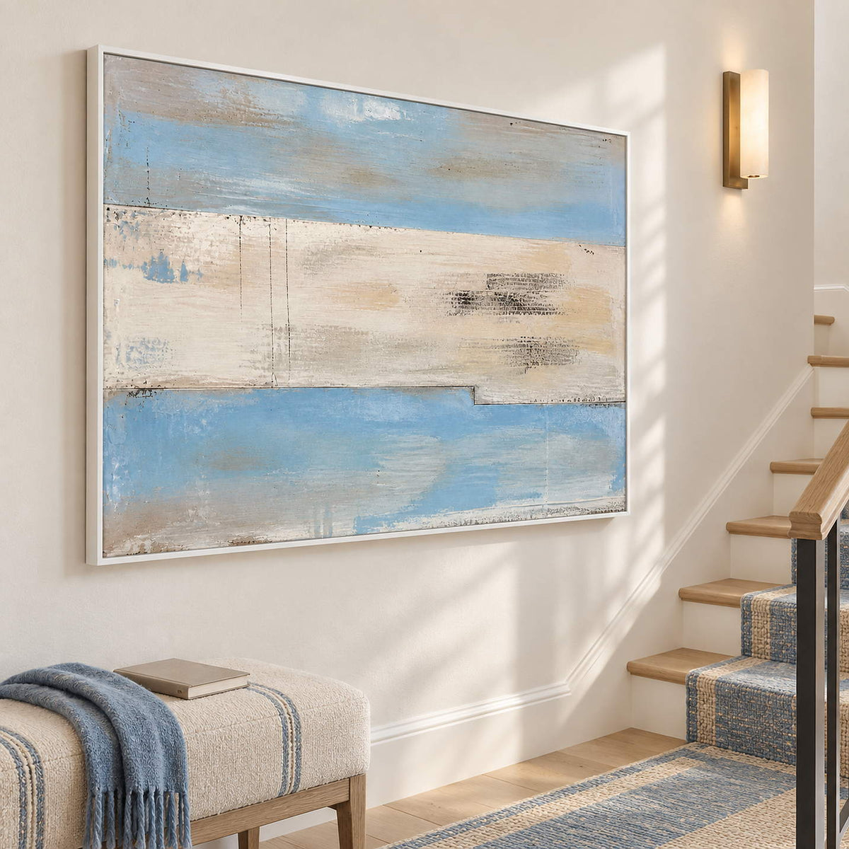 Pale blue and ivory coastal abstract painting with sand and charcoal bands in a white frame on a stair landing.