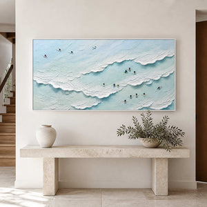 Pale blue coastal artwork above a stone console in a bright entryway.