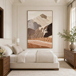 Wood framed earthy mountain artwork beside a cream bed and wooden dresser.