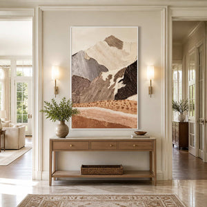 White framed mountain artwork above a wooden console between warm hallway sconces.