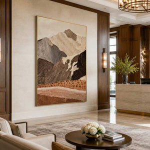 Gold framed mountain artwork beside a stone reception counter in a wood paneled hotel lobby.
