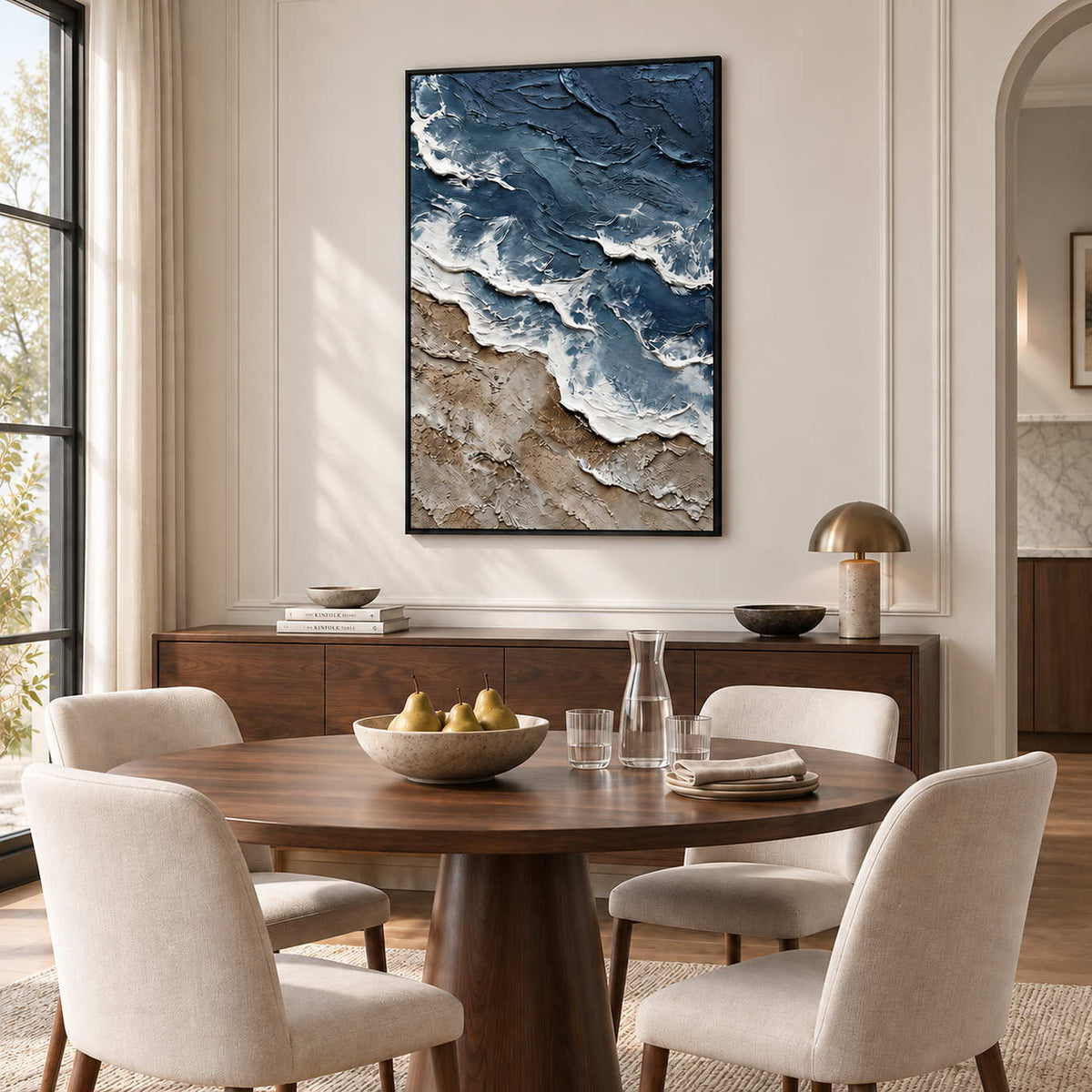 Beyond the Shore in a black frame above a wood sideboard behind a round table with cream dining chairs.